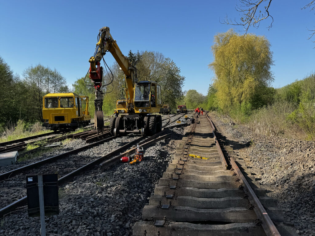 Bauzug und Bagger in Baustelle im Bahnhof Griedel