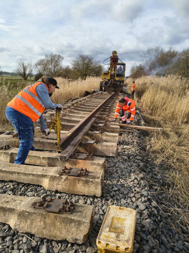 Die Feinarbeit ist Muskelkraft, wenn der Bagger die Schienenstücke legt